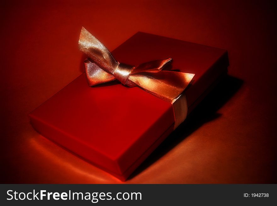 A red gift box with a golden ribbon. A red gift box with a golden ribbon.