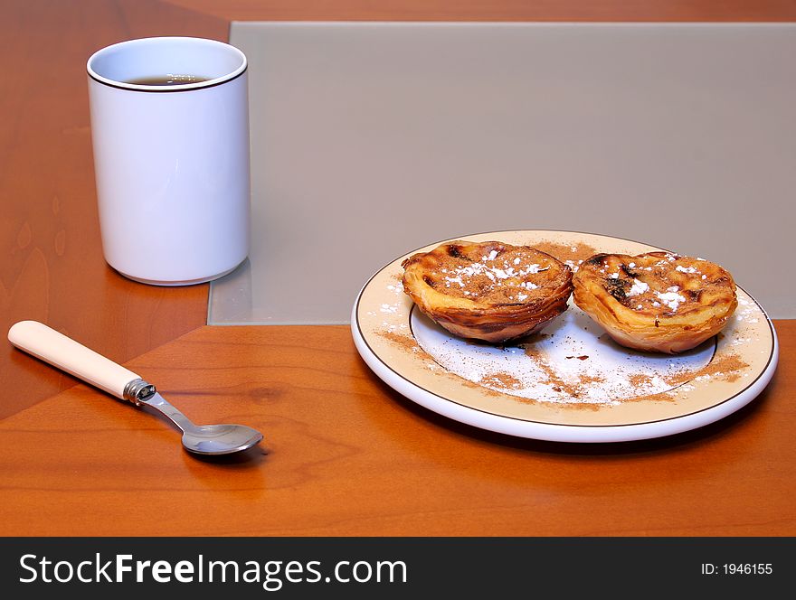 A coffee cup and two cream cakes for breakfast or a snack. A coffee cup and two cream cakes for breakfast or a snack