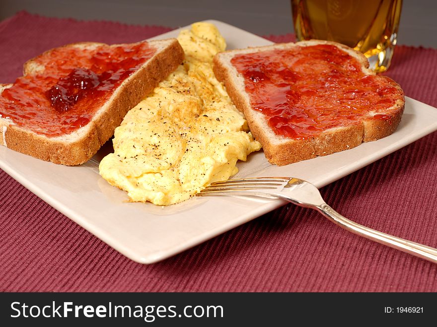 An omelette with toast, strawberry jam and apple juice