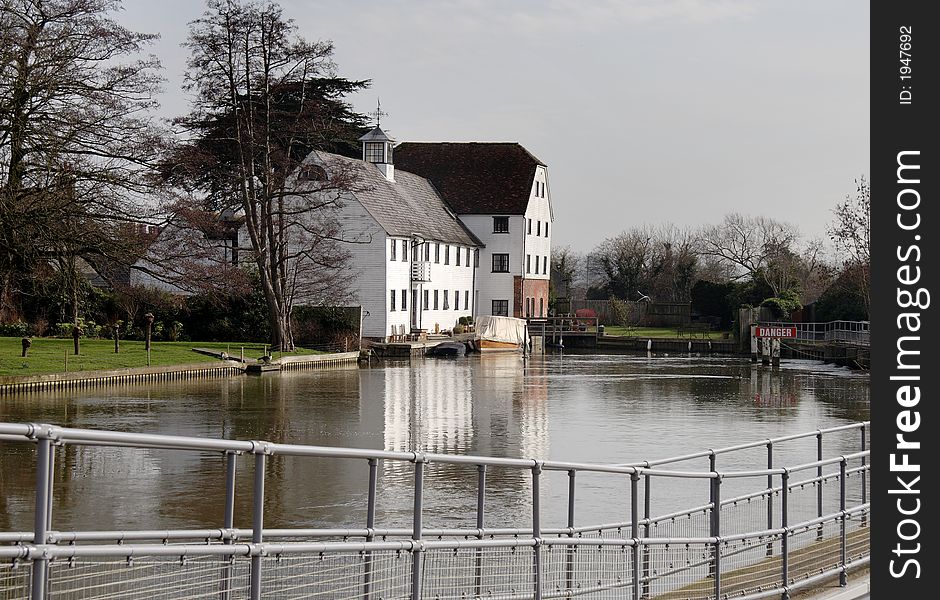 Winter scene of a an Historic Riverside Mill House with Boats moored to the front