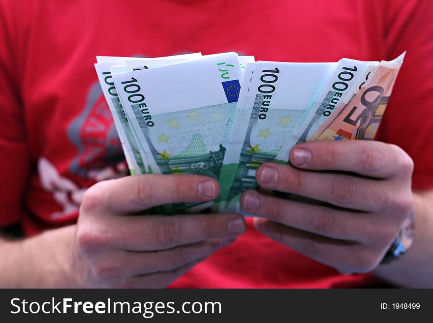 A men in the red t-shirt give 1500 euros in the hand. A men in the red t-shirt give 1500 euros in the hand