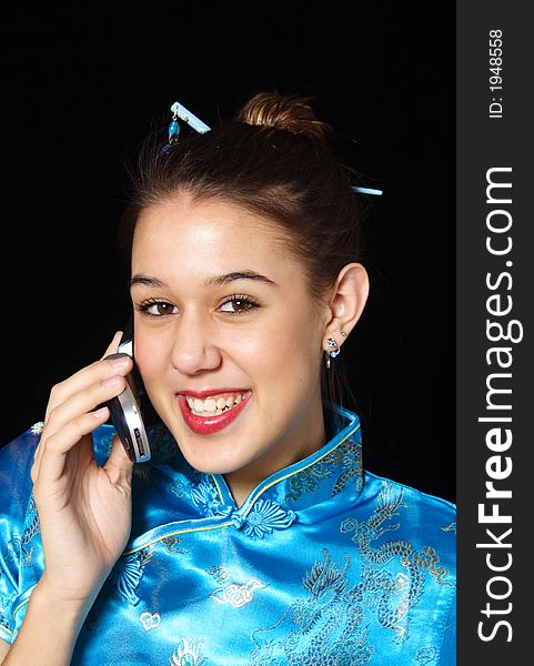 A young woman, in oriental dress smiles as she talks on her cell phone. A young woman, in oriental dress smiles as she talks on her cell phone.