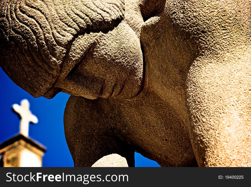 Sculpture of man praying with cross