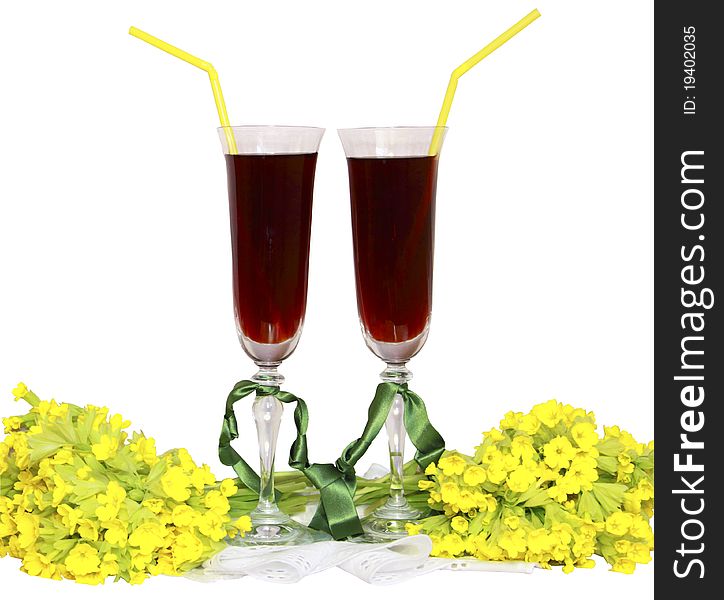 Two glass glasses with wine tubes for a cocktail and bouquets yellow field flowers