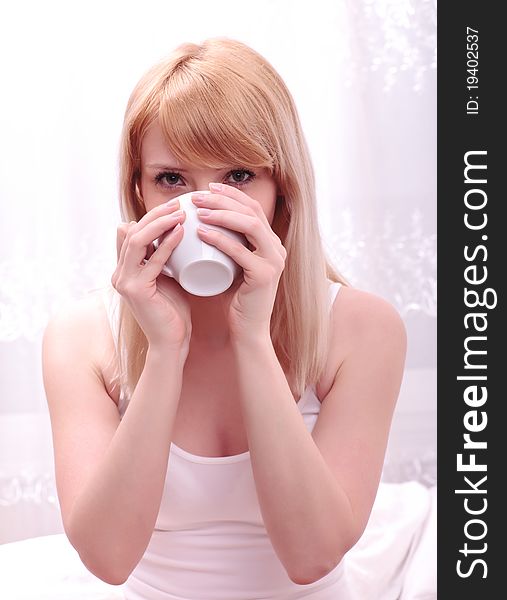 Young woman in bed holding a cup of coffee after she waken up. Young woman in bed holding a cup of coffee after she waken up