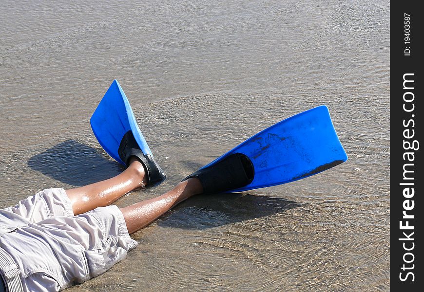 Boy s legs wearing swim fins on the beach