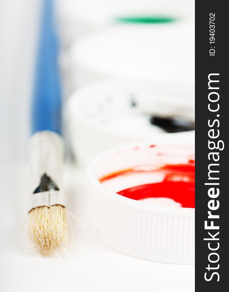 Macro view of brush and covers of gouache paint cans