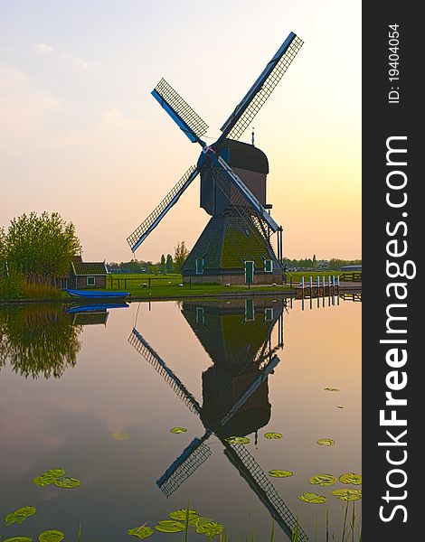 HDR image of a windmill in the evening sunset after the rain, casting a perfect reflection on the water in the canal. HDR image of a windmill in the evening sunset after the rain, casting a perfect reflection on the water in the canal.