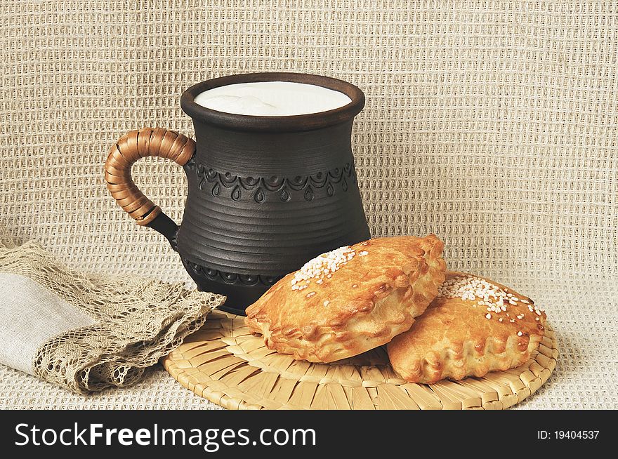 Pies with a stuffing and milk in a ceramic cup