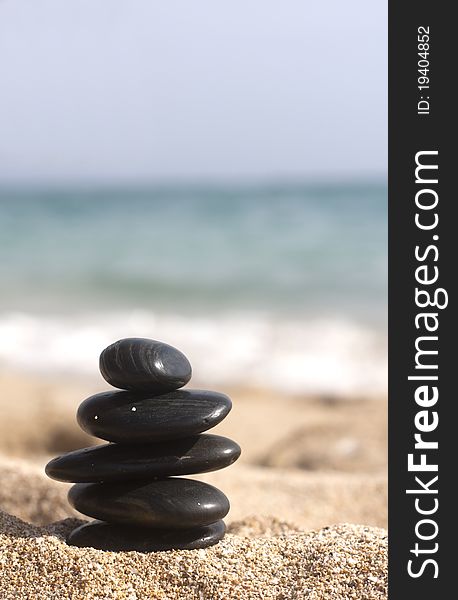 Five black stones pyramid on the sandy beach