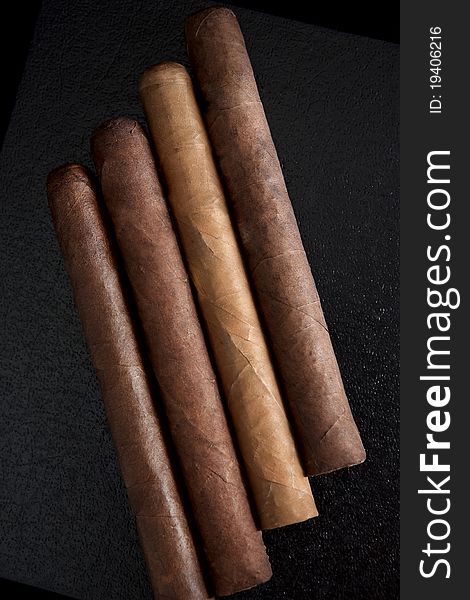 Four cigars on a dark background.