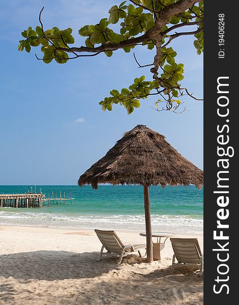 Straw umbrella and two chaise lounges on an empty sea beach. Straw umbrella and two chaise lounges on an empty sea beach