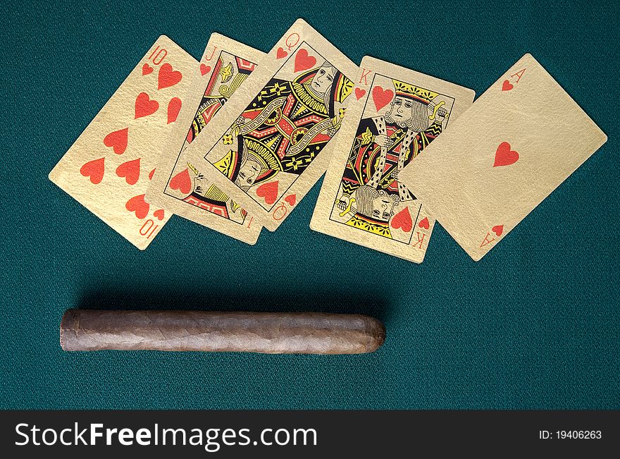 Cigar and playing cards on a green background.