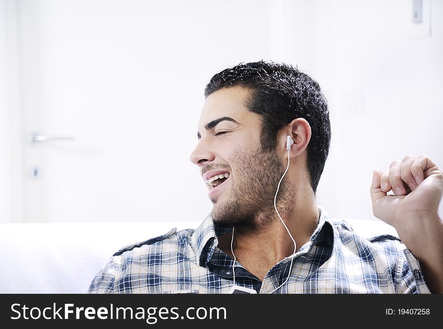 Young man listening music in home interior on the white background. Young man listening music in home interior on the white background