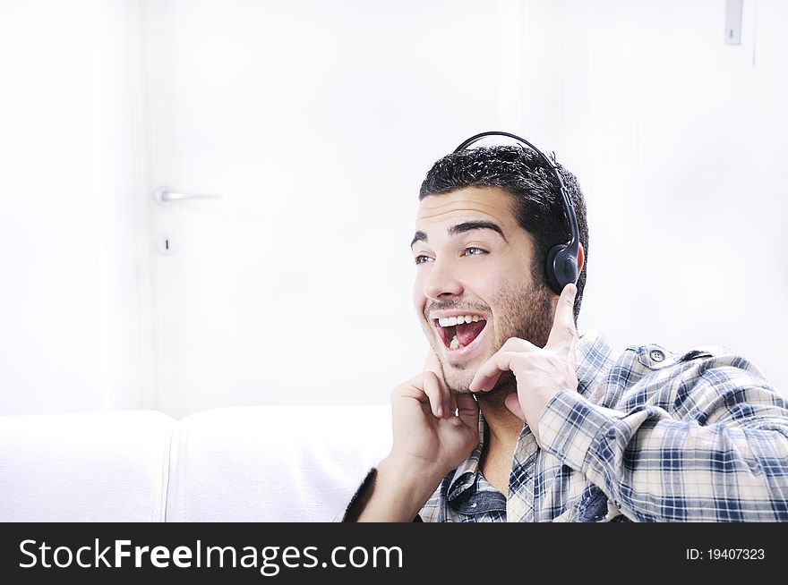 Young man listening music in home interior on the white background. Young man listening music in home interior on the white background