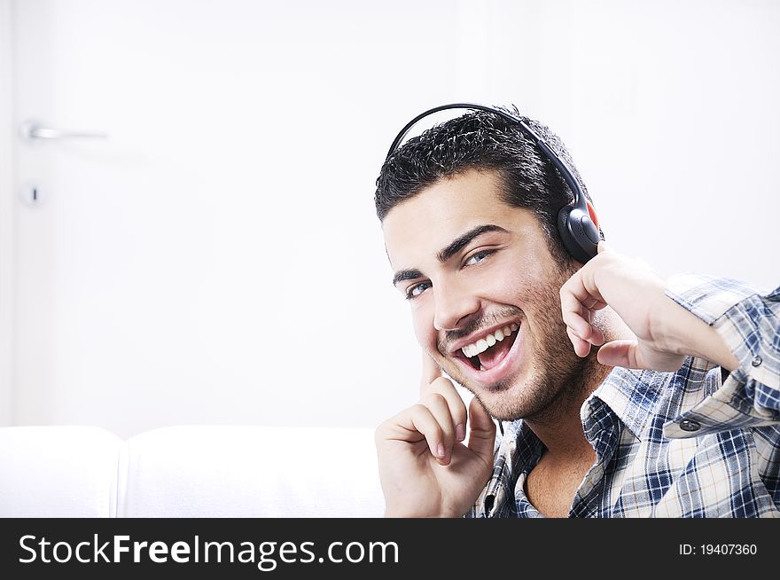 Young man listening music in home interior on the white background. Young man listening music in home interior on the white background