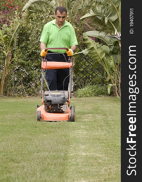 A gardener is cutting grass with machine. A gardener is cutting grass with machine