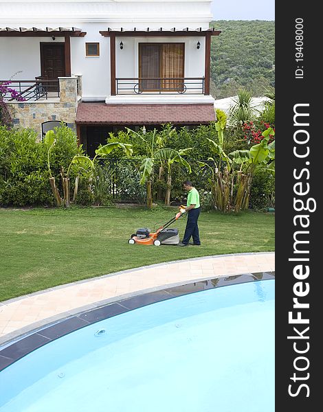 A gardener is cutting grass with machine. A gardener is cutting grass with machine