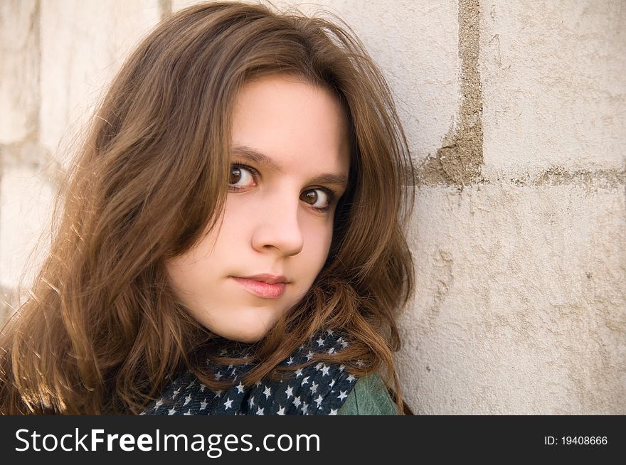 Portrait of the beautiful teenage girl on a brick background