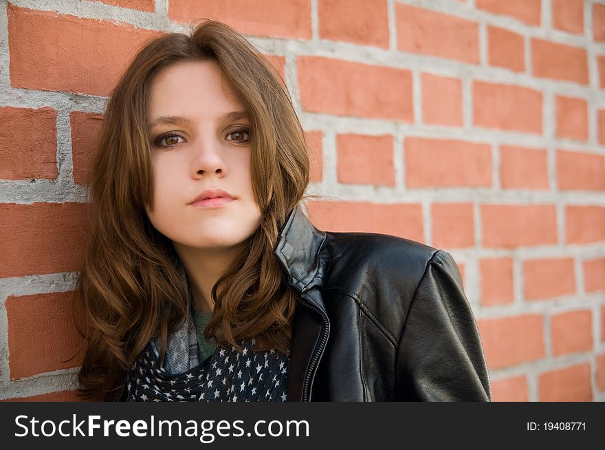 Portrait of the beautiful teenage girl on a brick background