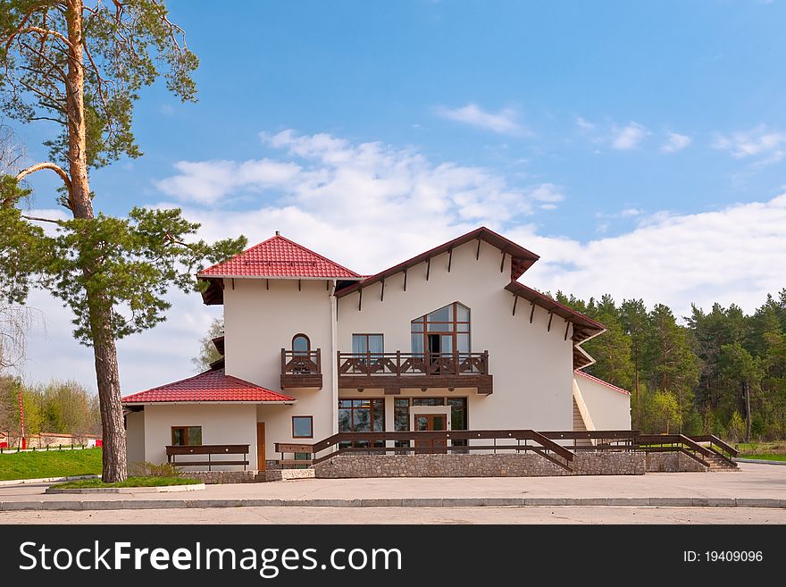 House with red roof against the backdrop of a pine forest