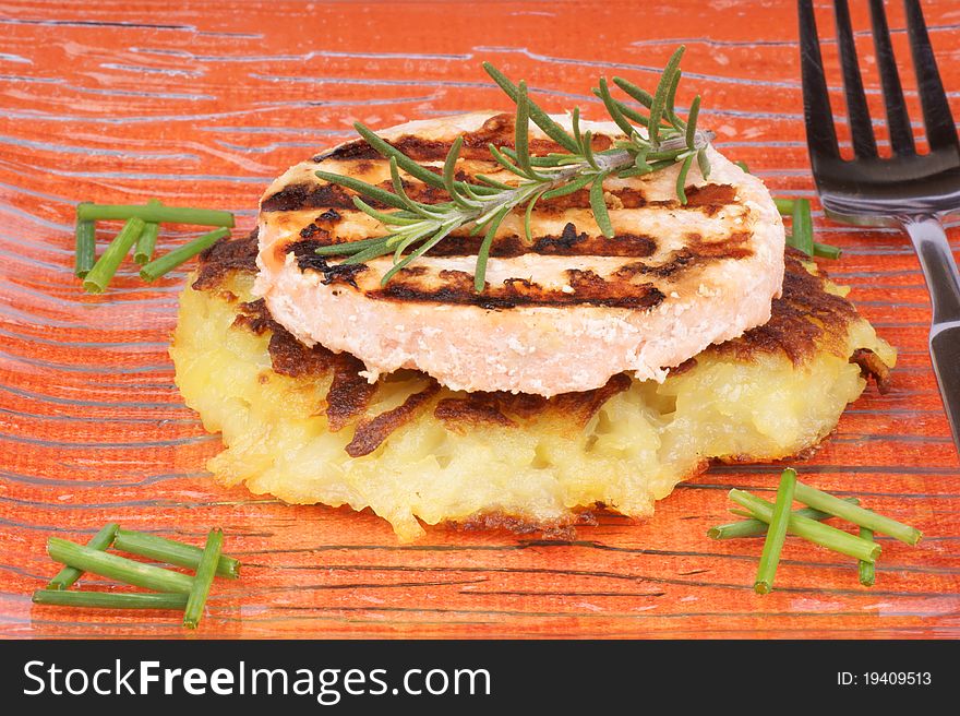 Roesti and grilled salmon with chives and rosemary over a glass dish