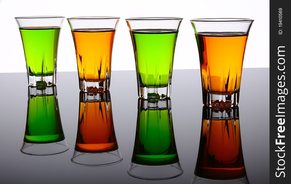 Four small shot glasses of alcoholic beverages