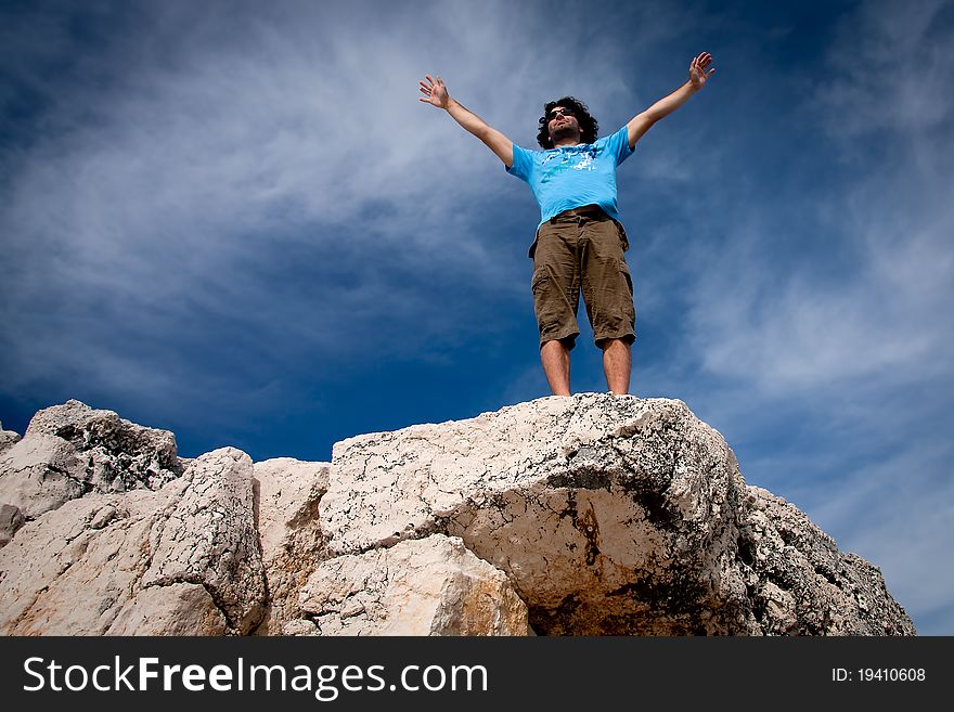 Man standing on top of the rock with outstreched arms. Man standing on top of the rock with outstreched arms