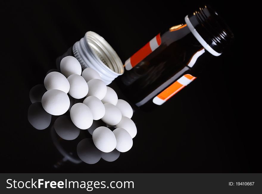 Pill bottle with whitepills on black background. Pill bottle with whitepills on black background