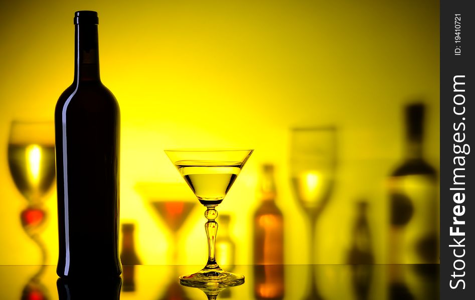 Dark bottle and glass on a background with the shadows of bottles