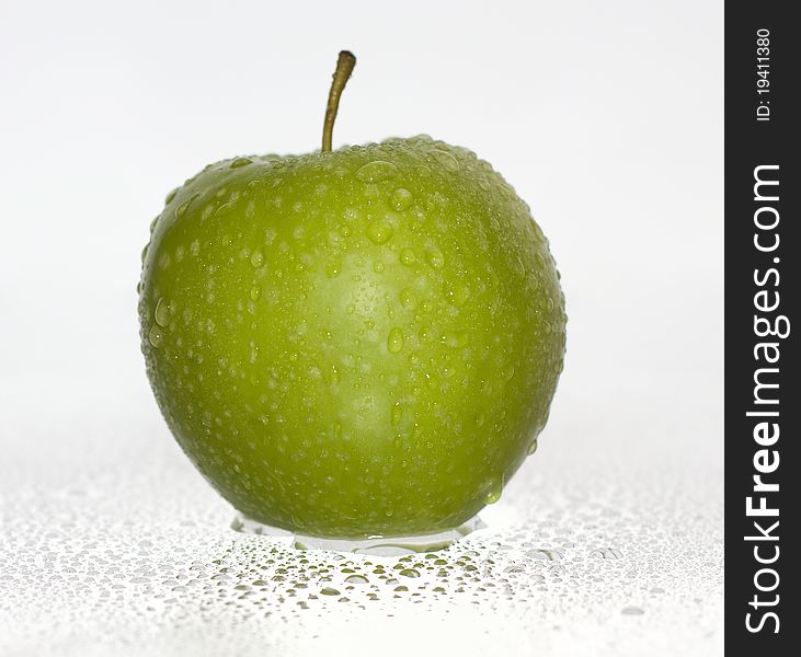 Green apple covered with water drops on a white background