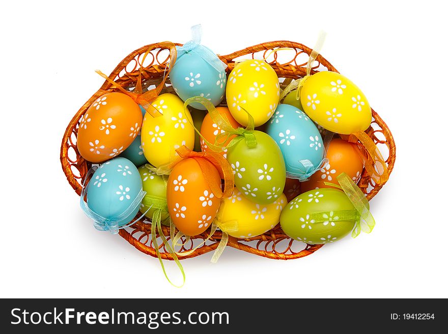 Color easter eggs in basket isolated on white. top view
