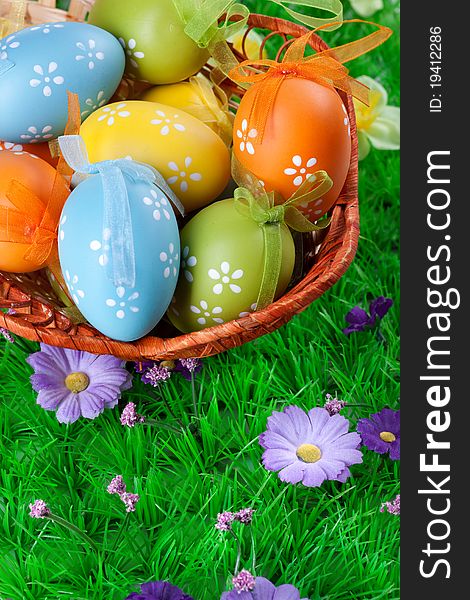 Color easter eggs in basket on the green grass