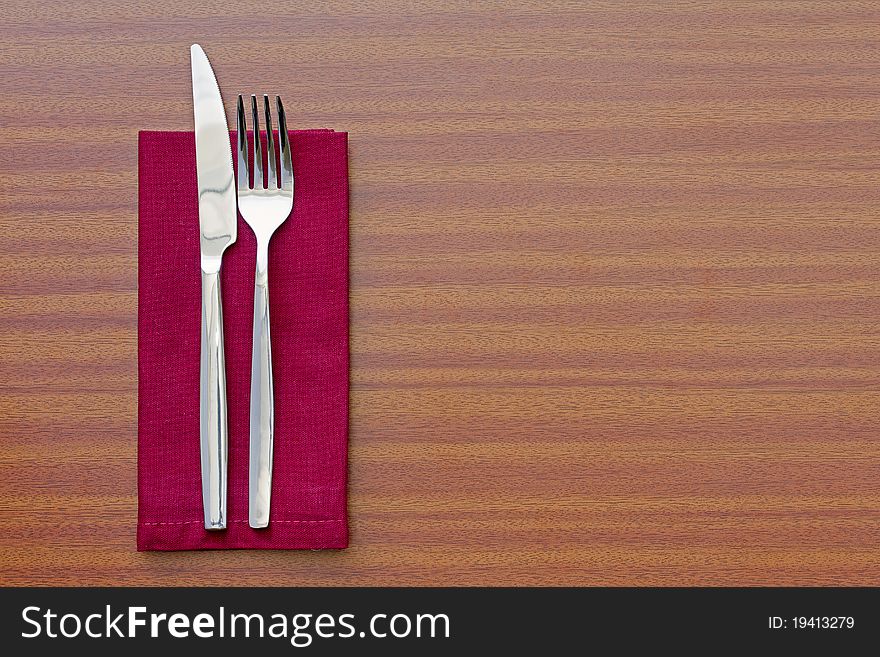 Knife and fork with red napkin on table