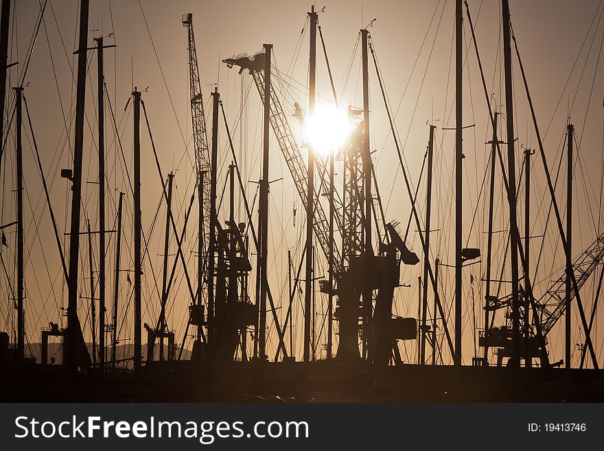 Docks on sunset, with the sun on the background, and with cranes and boats. Docks on sunset, with the sun on the background, and with cranes and boats