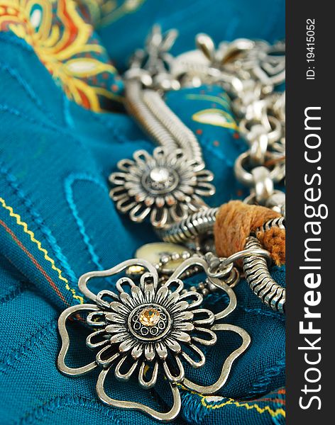 Silver necklace with flowers on the blue fabric in East style background. Silver necklace with flowers on the blue fabric in East style background.