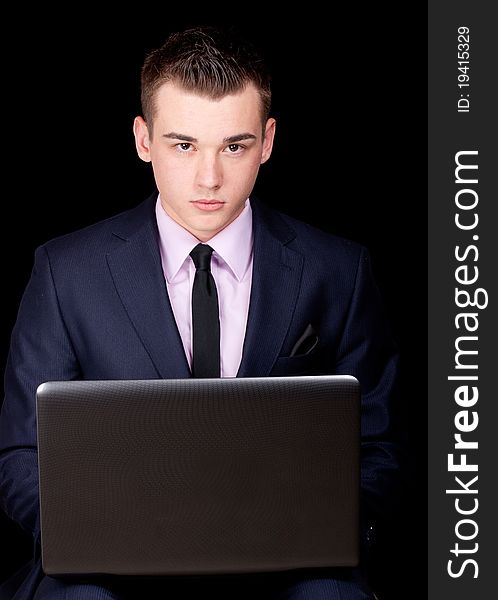 A photograph of a young executive sitting down with his laptop. A photograph of a young executive sitting down with his laptop.