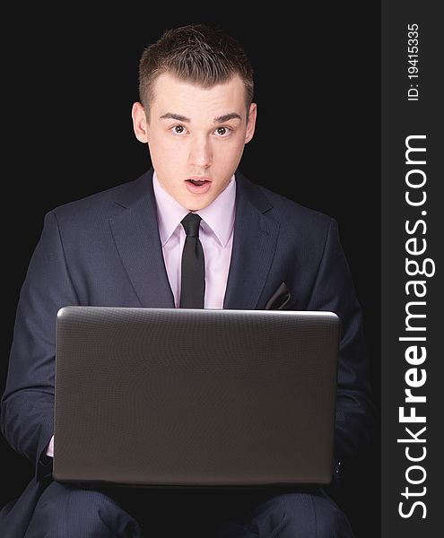 A photograph of a young executive who is excited by what he sees on his laptop computer. A photograph of a young executive who is excited by what he sees on his laptop computer.