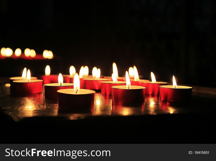 Several lighted red candles in the church