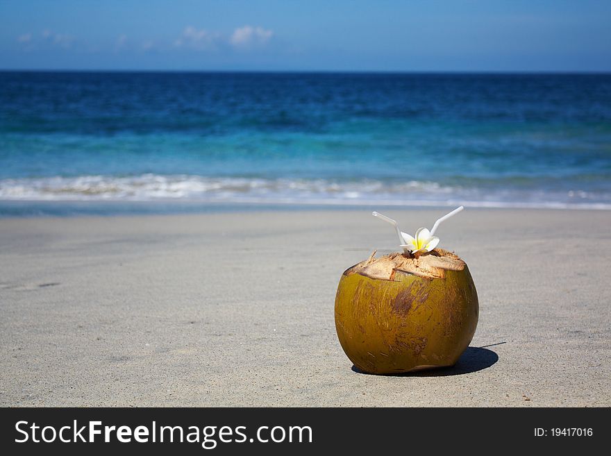 Coconut on tropical beach with plumeria