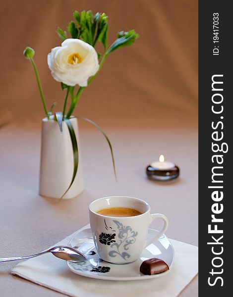 Cup of coffee with flower and candle on the table