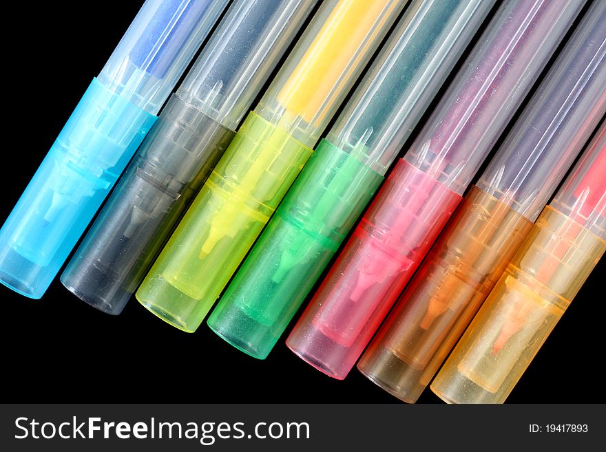 Collection of colorful pens over black background
