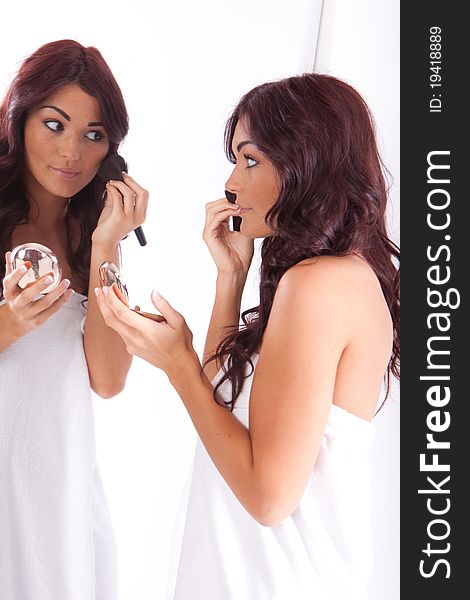 Happy brunette woman applying makeup on white. Happy brunette woman applying makeup on white