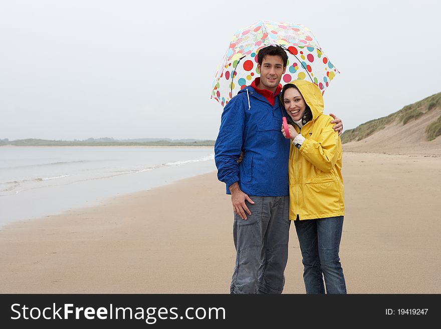 Young Couple On Beach With Umbrella