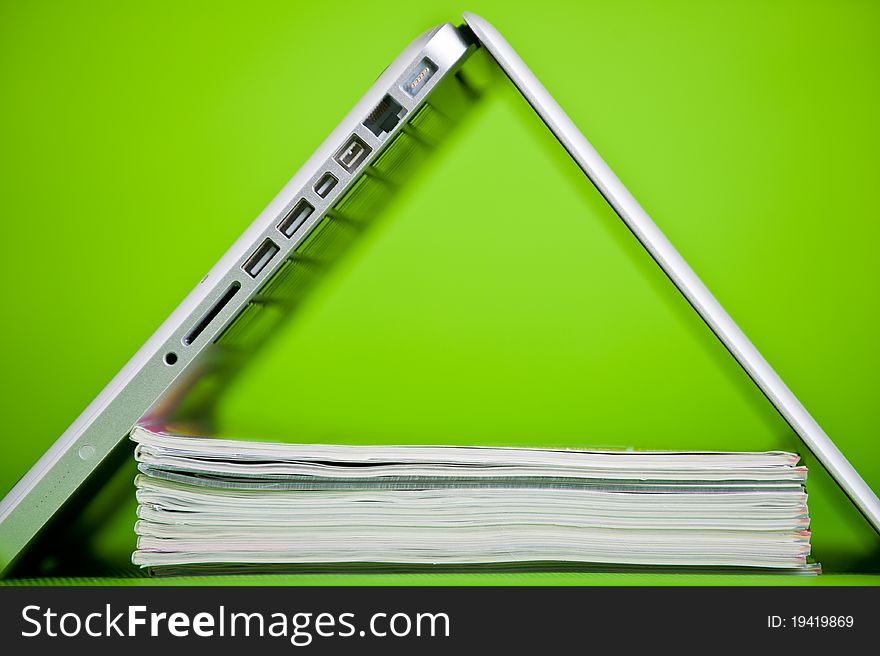 Stack of books and a laptop isolated over a green background. Stack of books and a laptop isolated over a green background