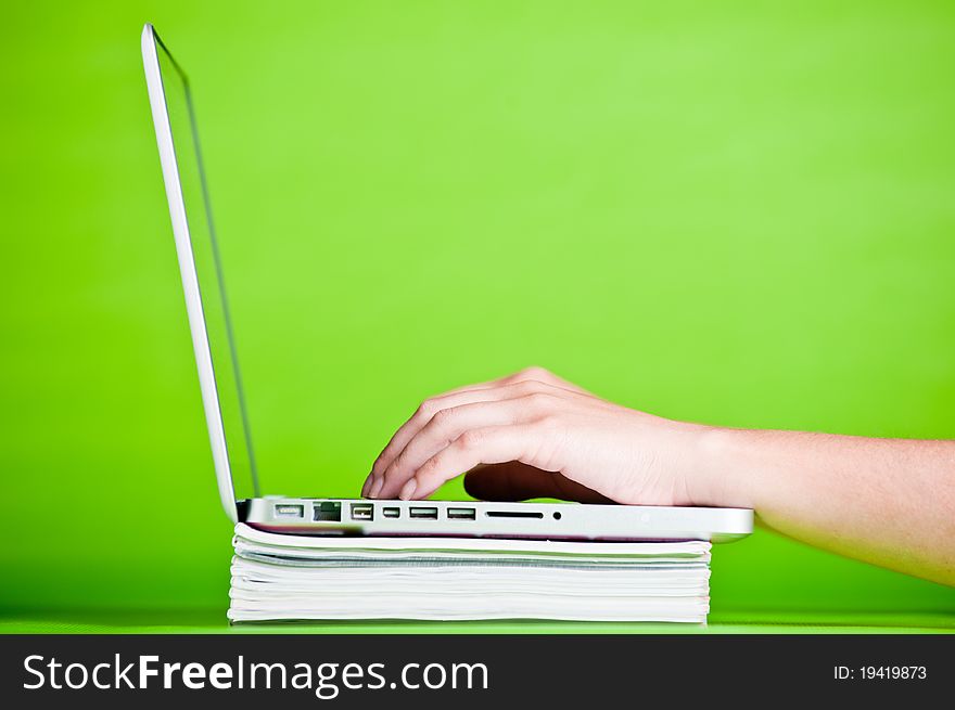 Stack of books and a laptop isolated over a green background. Stack of books and a laptop isolated over a green background