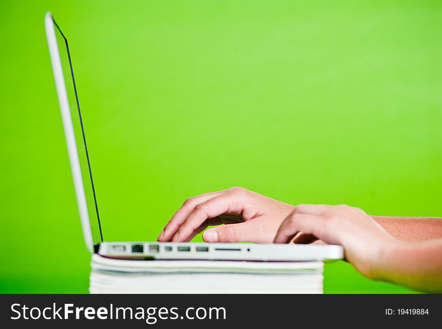 Woman using a laptop on stack of books isolated over a green background. Woman using a laptop on stack of books isolated over a green background