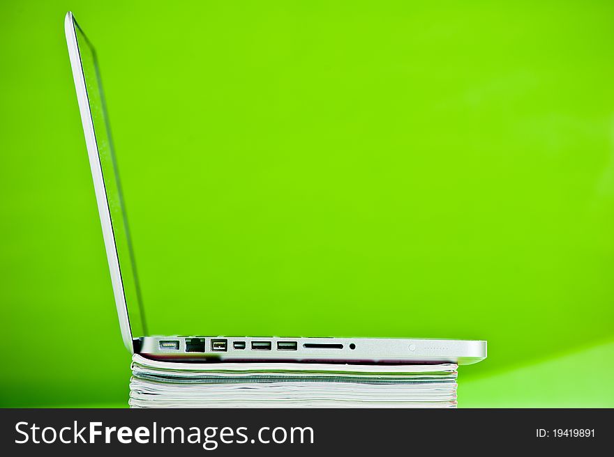 Stack of books and a laptop isolated over a green background. Stack of books and a laptop isolated over a green background