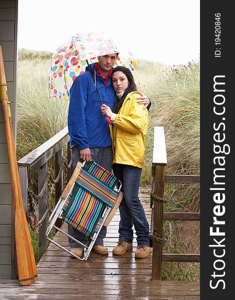 Young couple on beach with umbrella unhappy