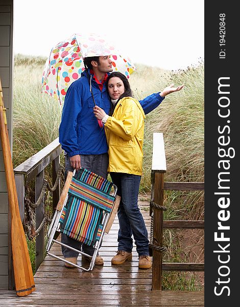 Young couple on beach with umbrella unhappy